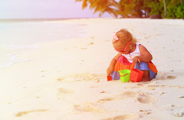 cute toddler girl playing with toys on beach