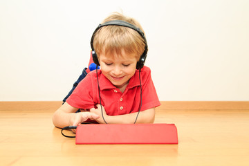 Naklejka premium little boy with headset using touch pad