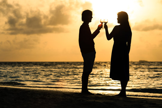 Silhouette of couple drinking wine at sunset beach