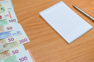 empty notepad with euro banknote, pen on table