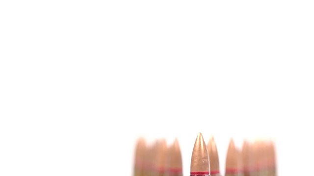 AK 47 ammunition. Defocus on a laying single bullet's bottom. From the back to the front. White background.