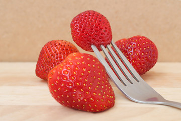stawberry and fork on wood plate