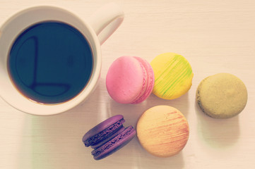 colorful macarons lay on with coffee cup