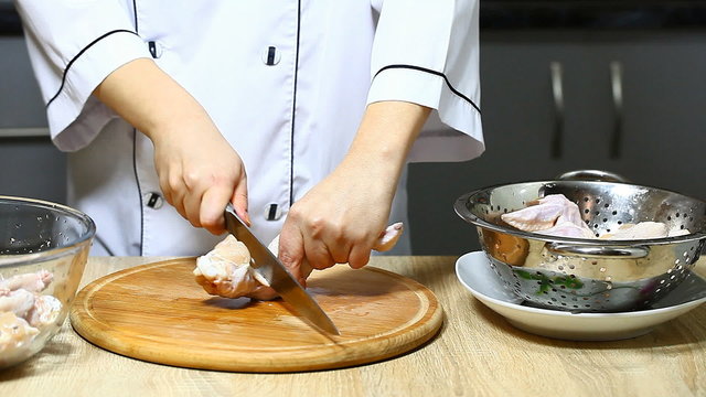the Cook cuts fresh raw chicken