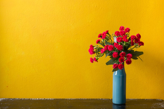 Red Flowers In Vase On Yellow Background