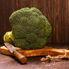 Fresh whole raw broccoli cabbage with vintage knife over grunge wooden background. Toned image. Selective focus