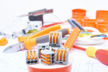 Modern connectors standing on junction box. Different electrical tools lying in background out of focus. Concept of electrical commercial.


