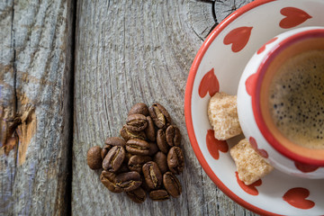 Coffee in white cup with hearts, beans, rustic wood background