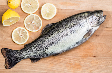 Fresh trout with lemons on a wooden board.