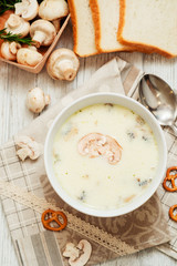 
mushroom soup with potatoes , carrots , green and white toast on a wooden background