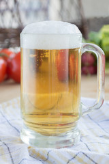 Glass of beer on plaid dishcloth with vegetables in background