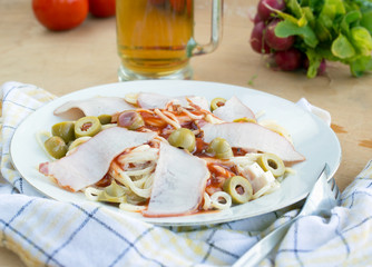 Pasta with ham ketchup and olives on white plate