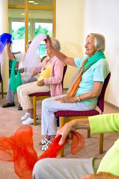 Enthusiastic women doing exercises in chairs.