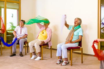 Excited women doing exercises in chairs.