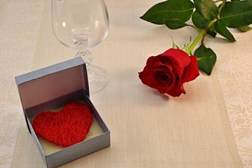 red rose on the table with a glass and a surprise
