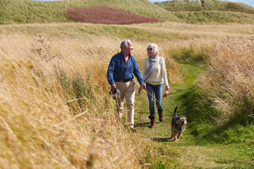 Senior Couple Taking Dog For Walk In Countryside - obrazy, fototapety, plakaty