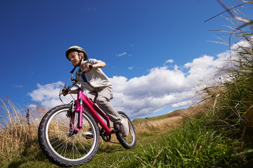 Obraz na płótnie Canvas Low Angle Shot Of Boy Riding Bike Through Countryside