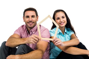 Smiling couple sitting on floor holding house shape