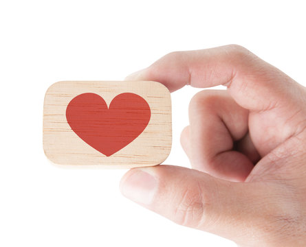 Hand holding a wooden block and red heart on white background