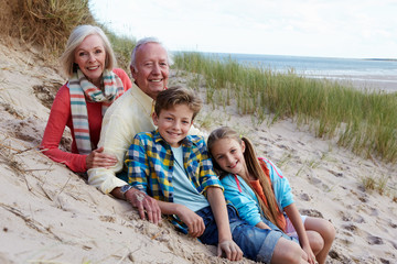 Portrait Of Grandparents With Children Sitting On Beach