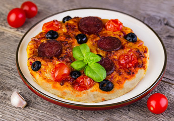 homemade hot pizza with a salami, tomatoes, olives