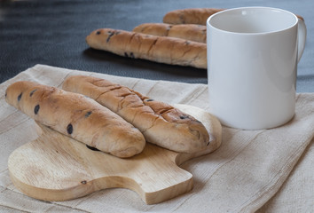 Raisin bread on wooden and coffee cup on fabric