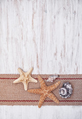 Fototapeta na wymiar Seashells and sackcloth on the old white wood