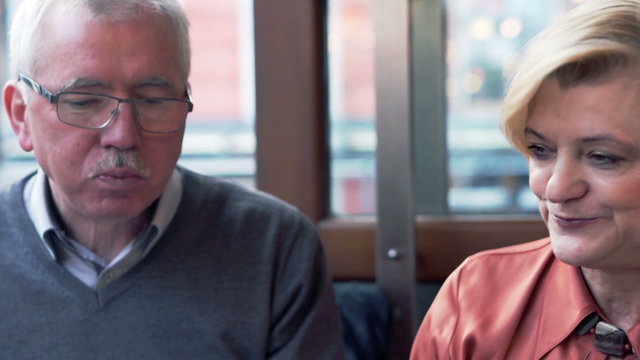 Middle aged couple sharing food and feeding each other in cafe in the city
