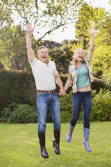 Fototapeta premium Cute couple jumping with arms in the air