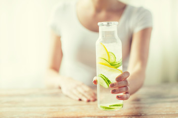 close up of woman with fruit water in glass bottle