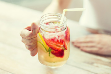 close up of woman holding glass with fruit water