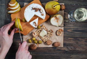 Hands cut pear on wood table with food. Top view