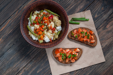 plate of rice with vegetables and sandwiches tomatoes on a rustic background