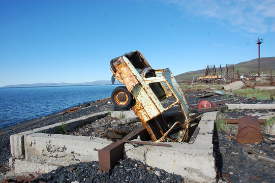 Old broken rusty abandoned car upside down at sea coast