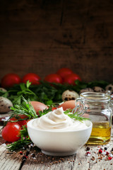 Homemade mayonnaise sauce in a white bowl, jar with olive oil, e