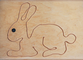Osterhase aus einer Schnur geformt, mit Holz-Hintergrund