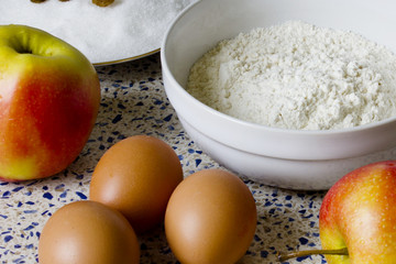 Ingredients for apple pie on the kitchen table. Flour, sugar, raisins, eggs and apples for homemade pastries.