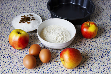 Ingredients for apple pie on the kitchen table. Flour, sugar, raisins, eggs and apples for homemade pastries.