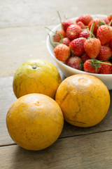 closeup three oranges with many strawberry background