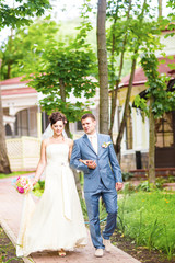 Naklejka premium Bride and Groom at wedding Day walking Outdoors on spring nature. Bridal couple, Happy Newlywed woman and man embracing in green park. Loving wedding couple outdoor