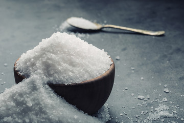 Salt. Coarse grained sea salt on granite - concrete  stone background with vintage spoon and wooden bowl.