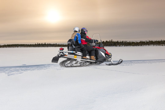 Couple Driving Snowmobile On Snow 