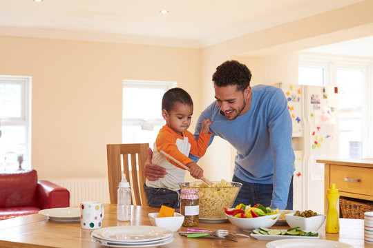 Father And Son Making Pasta Salad In Kitchen