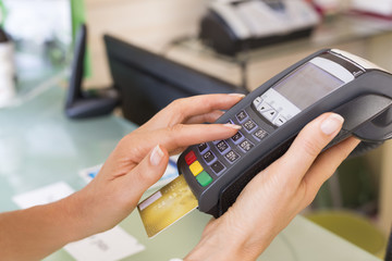 Close up of woman's hands with credit card swipe through terminal 