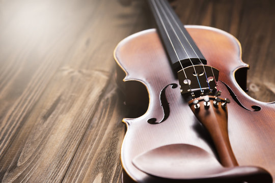 Old violin on wooden background.