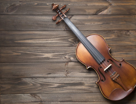 Old violin on wooden background.
