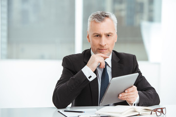 Naklejka premium Aged businessman in office with big window