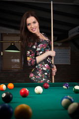 Glamorous brunette sexy woman standing next to the pool table