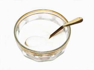 Bowl of sugar and spoon on white background