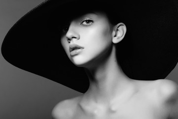 Portrait of a beautiful young girl in a hat, black and white photography in the studio